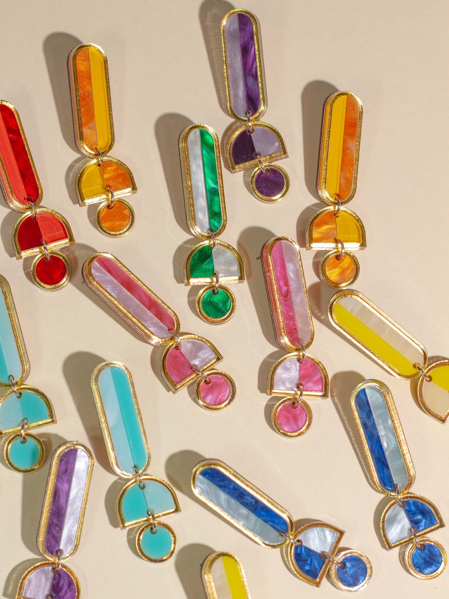 Colorful earrings with gold accents on a beige background