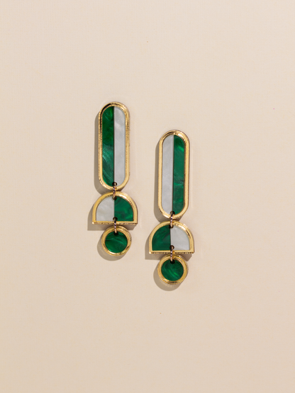 Pair of gold and green earrings on a beige background