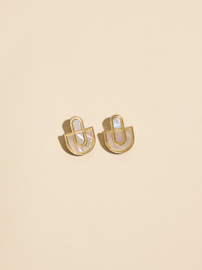 Gold earrings with a central gemstone on a beige background