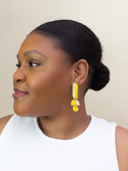 Woman wearing yellow earrings against a neutral background