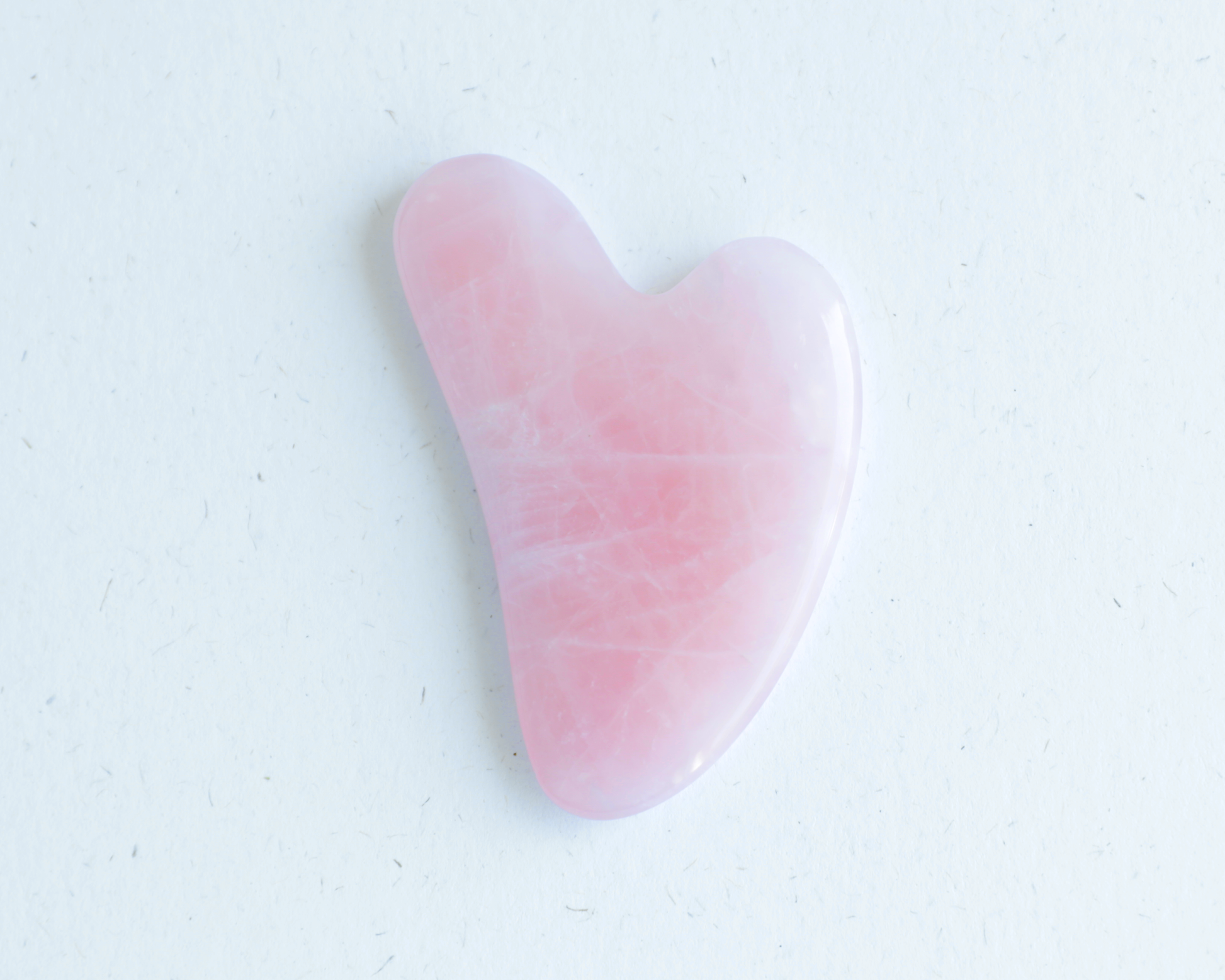 Pink gua sha tool on a white background