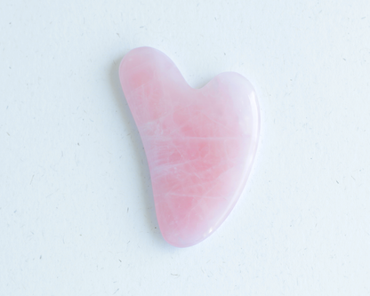 Pink gua sha tool on a white background